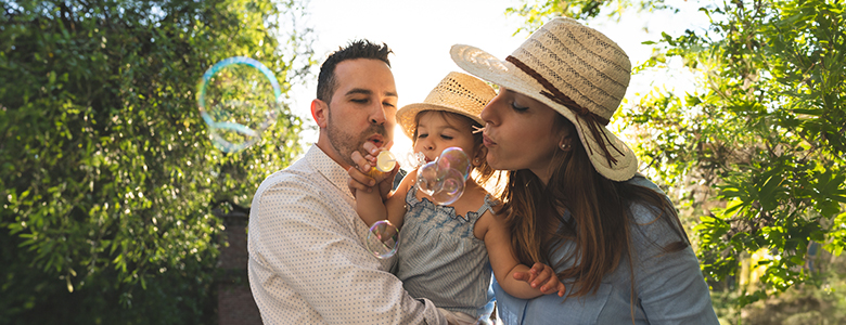 A man and woman blow bubbles with a toddler A man and woman blow bubbles with a toddler